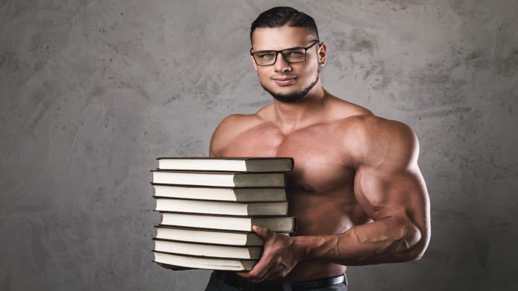 A clever bodybuilder holding a pile of books