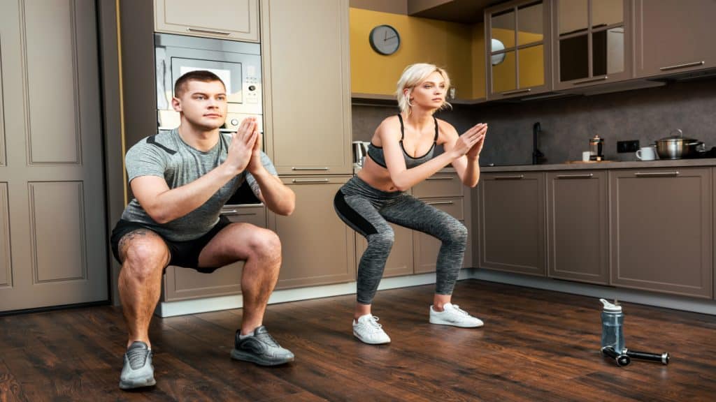 A couple doing squats at home