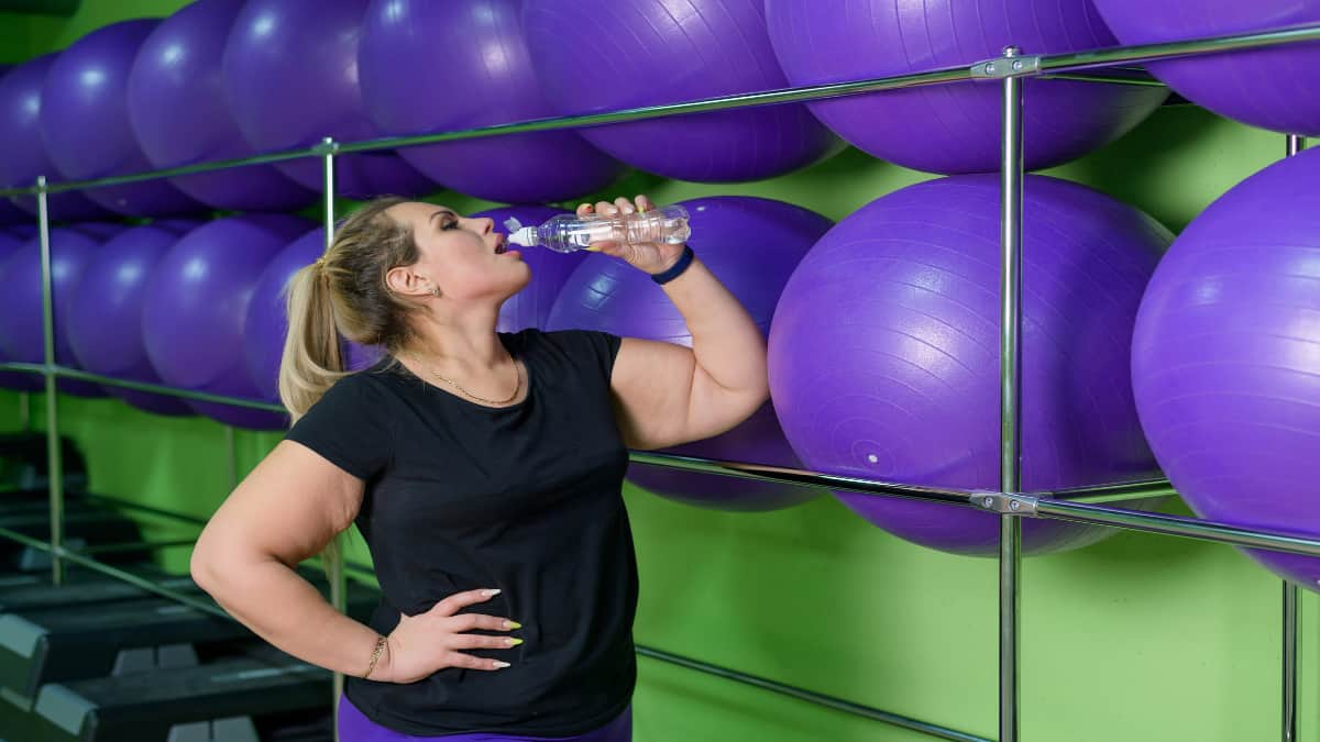A woman with fat forearms drinking some water