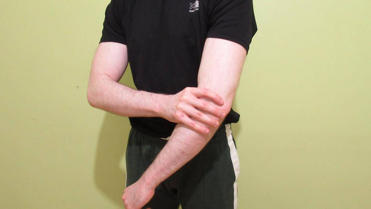 A man holding his arm after feeling a painful forearm cramping sensation