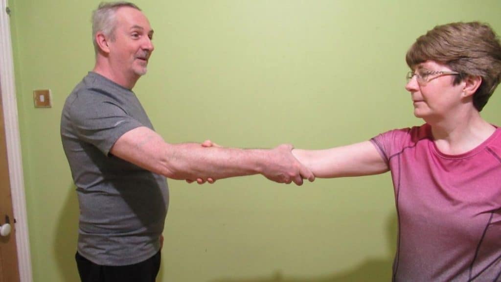 A man and a woman greeting each other with a forearm handshake