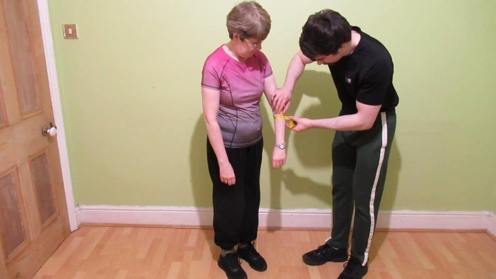 A man taking a woman's forearm measurements