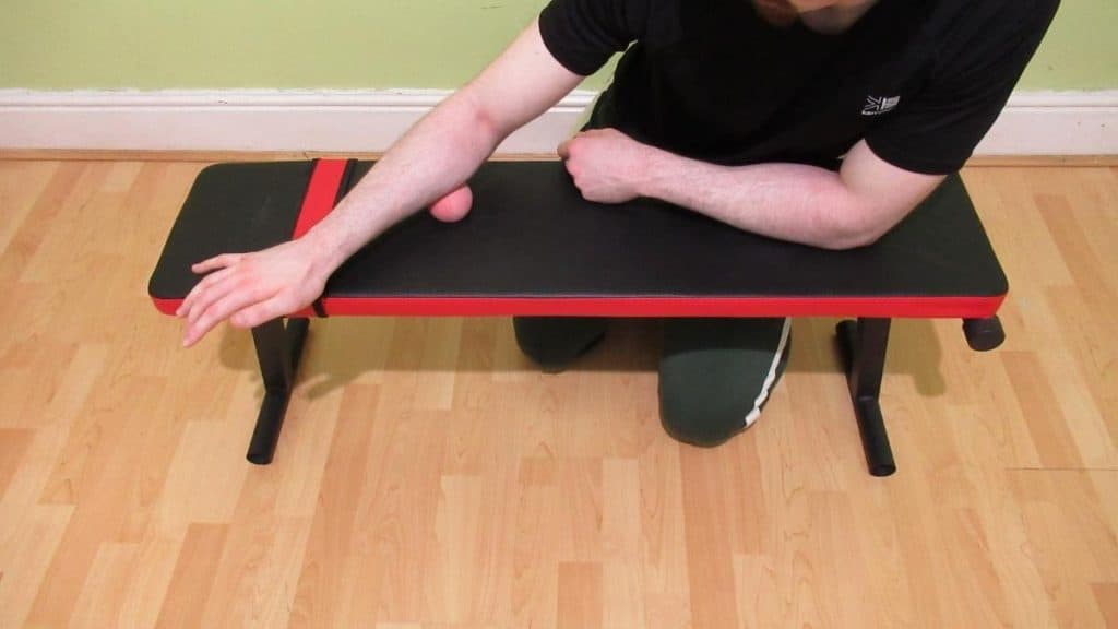A man performing forearm myofascial release with a lacrosse ball