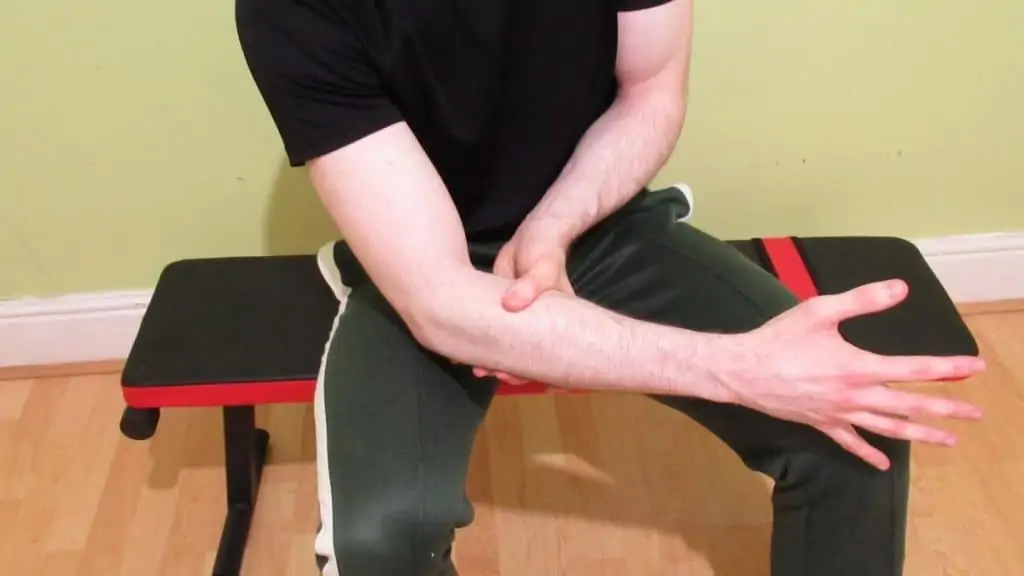 A man experiencing forearm pain after lifting weights