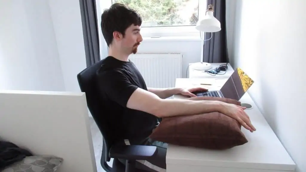 A man at his desk resting his forearm because it hurt after doing pull ups