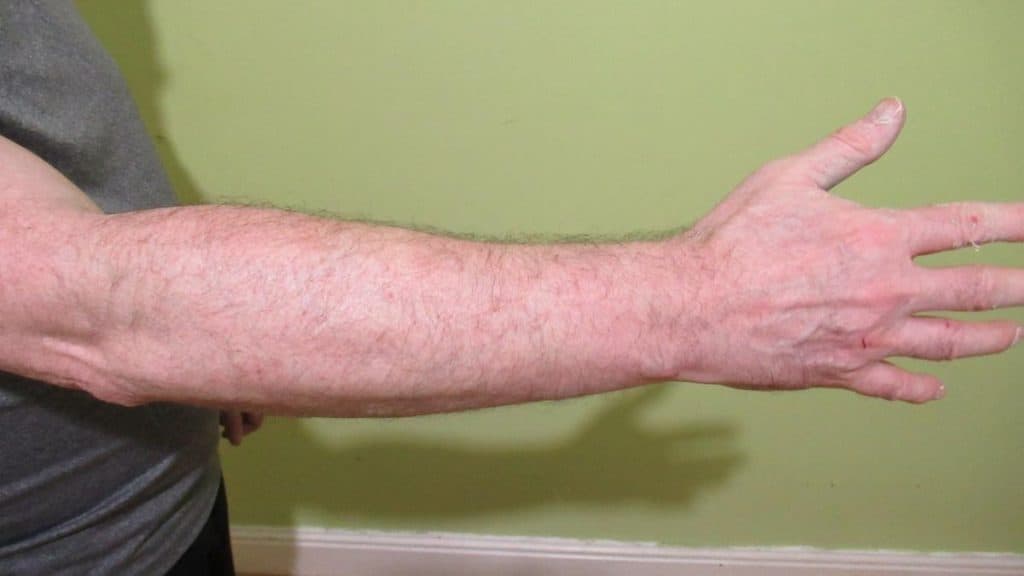 A man showing his 12 inch forearms