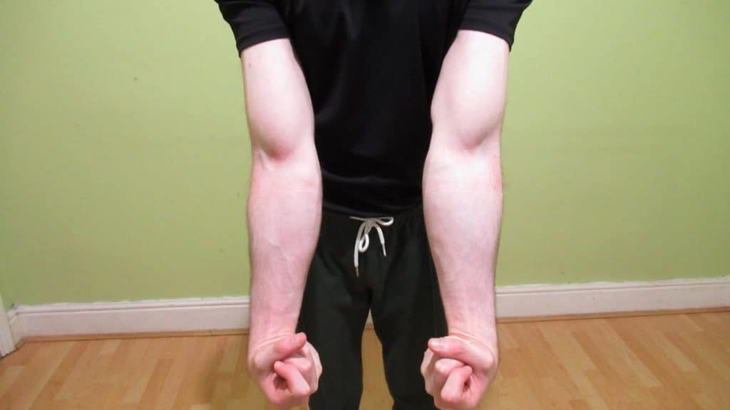 A man flexing his muscular 13 inch forearms