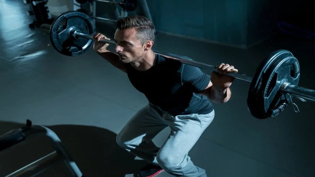 A man squatting weights in the gym