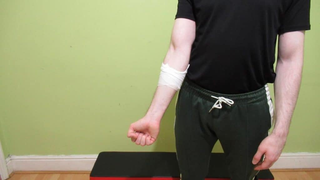 A man compressing his lower arm with a medical bandage because he has muscle cramp in his forearm