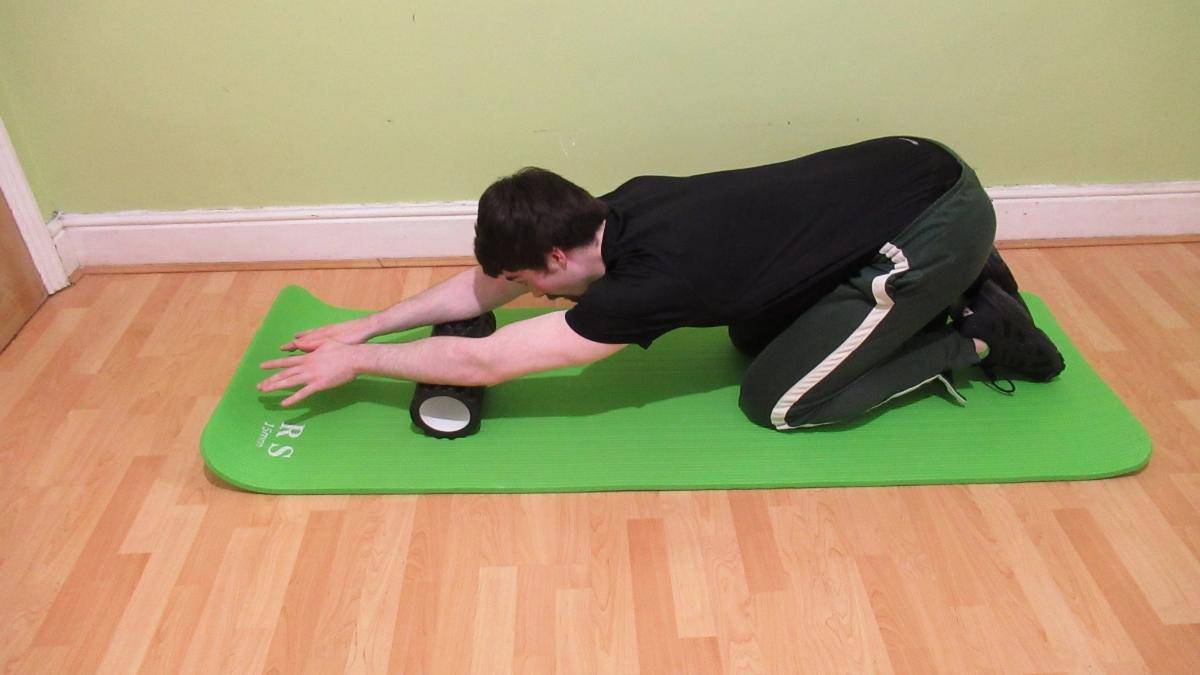 A man doing self myofascial release with a foam roller for his forearms