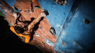 A man making use of his musculaar forearms while rock climbing