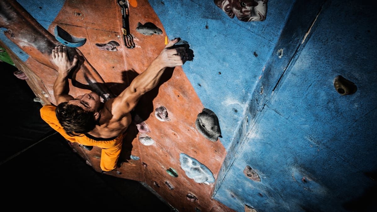 A man making use of his musculaar forearms while rock climbing
