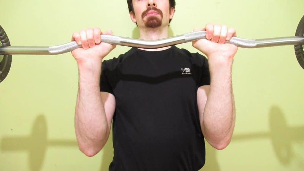A man holding a barbell with a thumbless grip