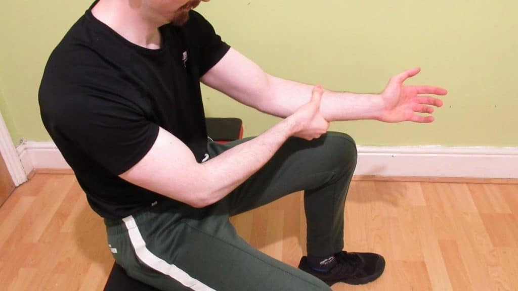 A man holding his tight forearm flexors