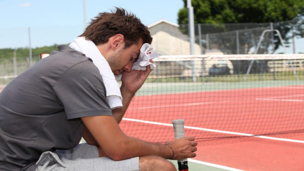 A tired tennis player sitting down