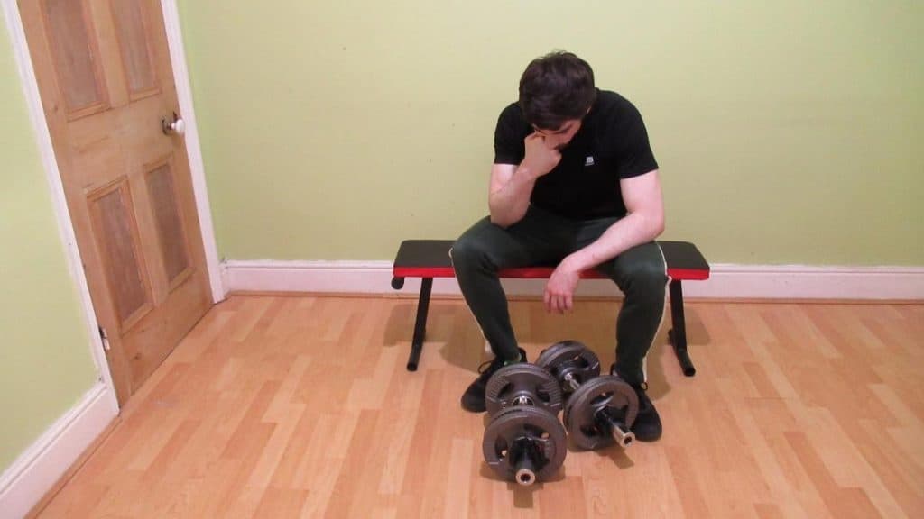 A tired weight lifter sat on a bench