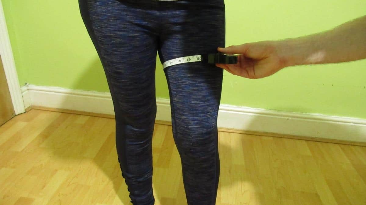 A person with a tape measure showing where to measure your thighs