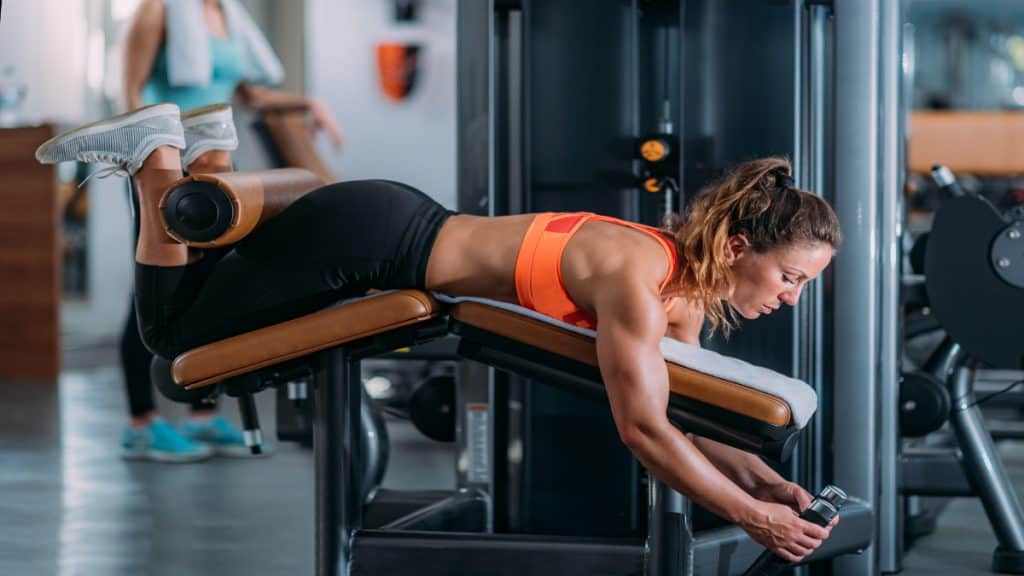 A woman performing hamstring curls at the gym