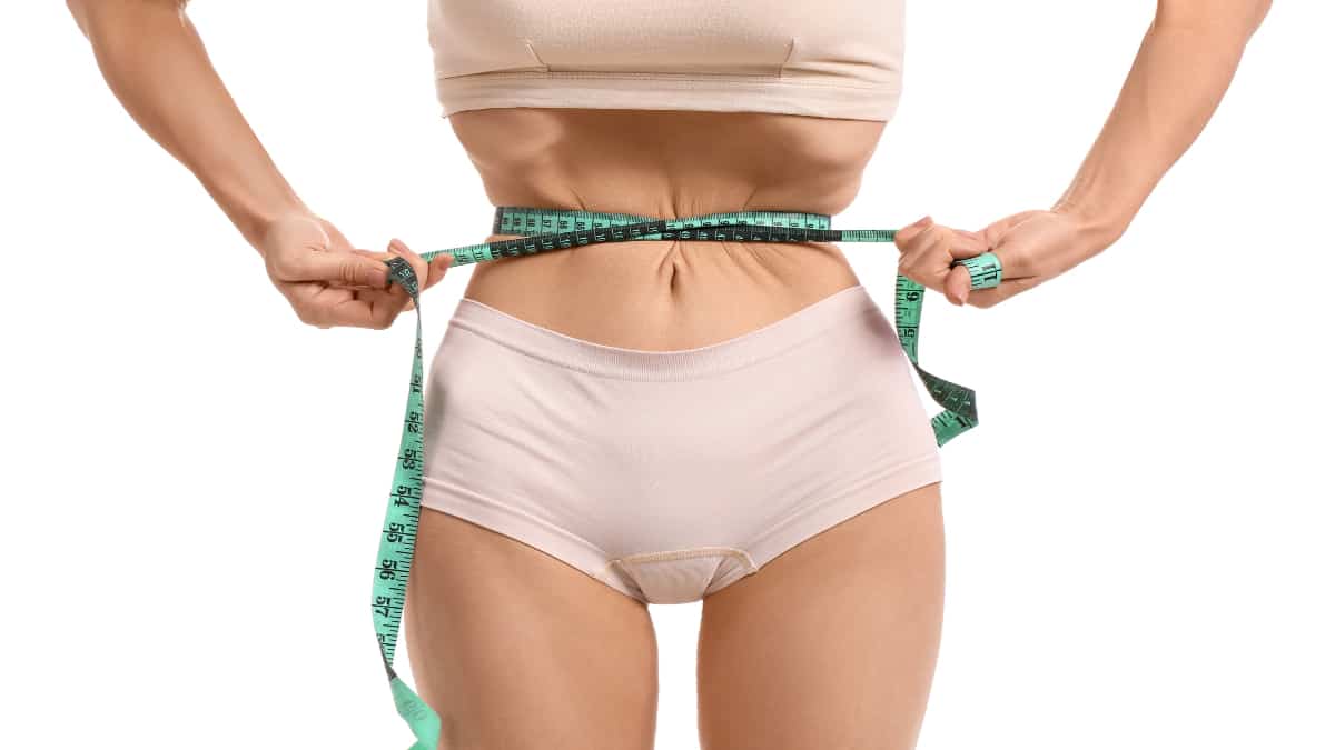 A skinny woman measuring her 16 inch waist