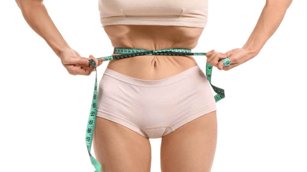 A woman measuring her 18 inch waistline