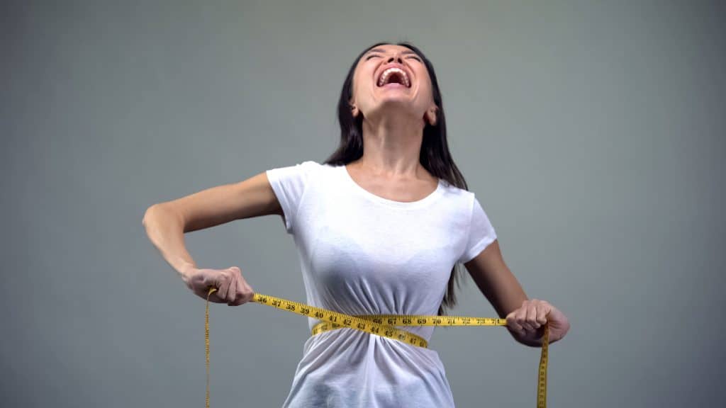 A screaming woman measuring her 21 inch waistline
