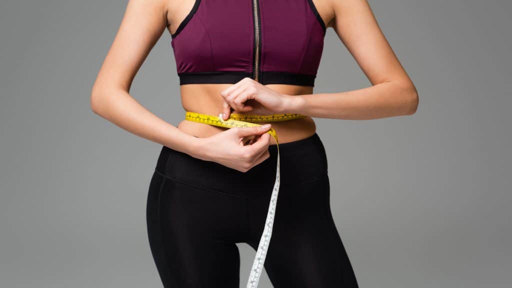 A woman wrapping a tape around her 26 in waist