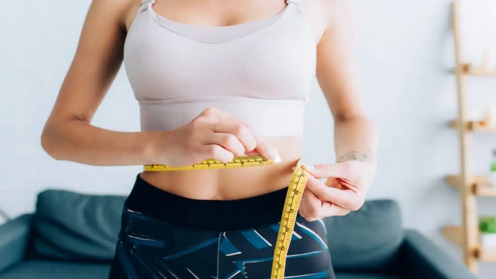 A woman measuring her 28.5 inch waist