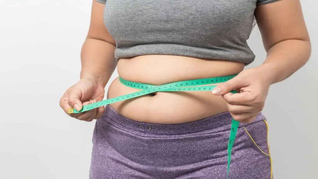 A woman holding a tape around her 34 inch waist