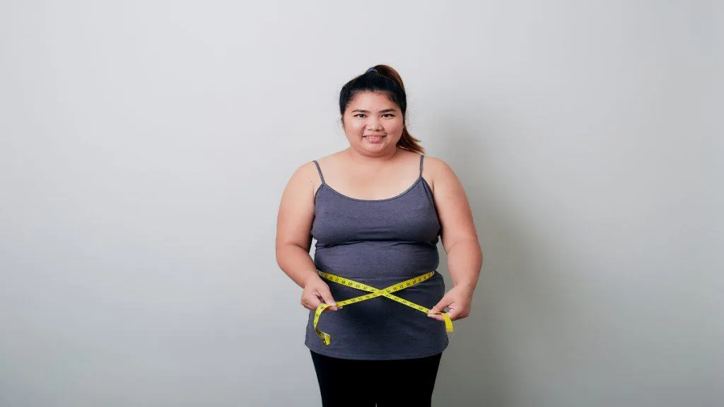 A woman with a 37 inch waist holding a tape measure