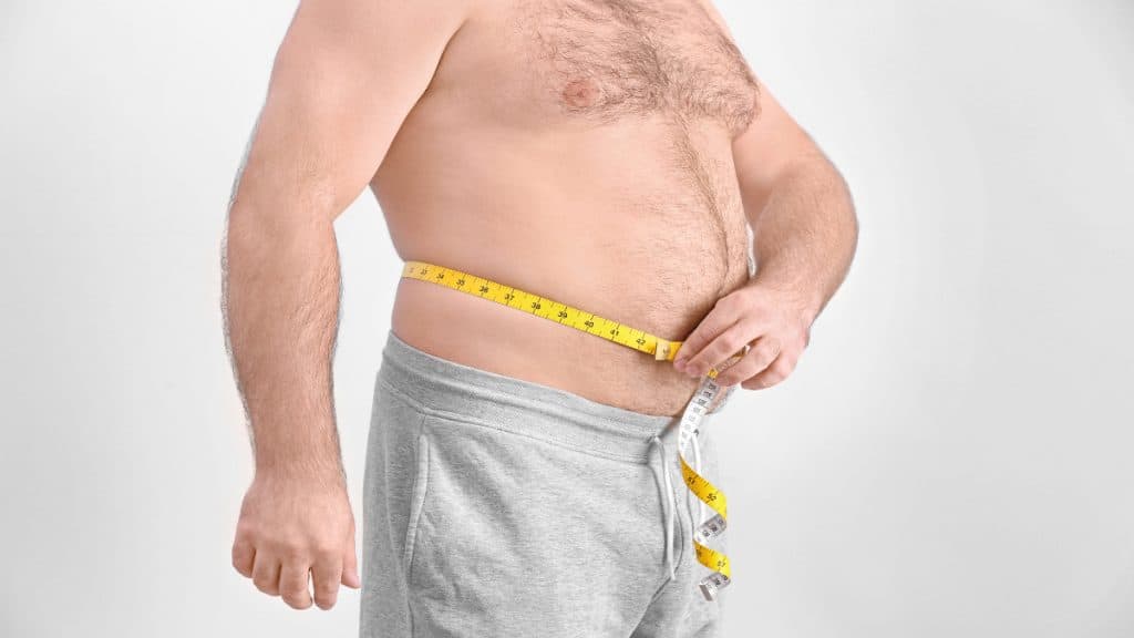 An overweight man measuring his 37.5 inch waist