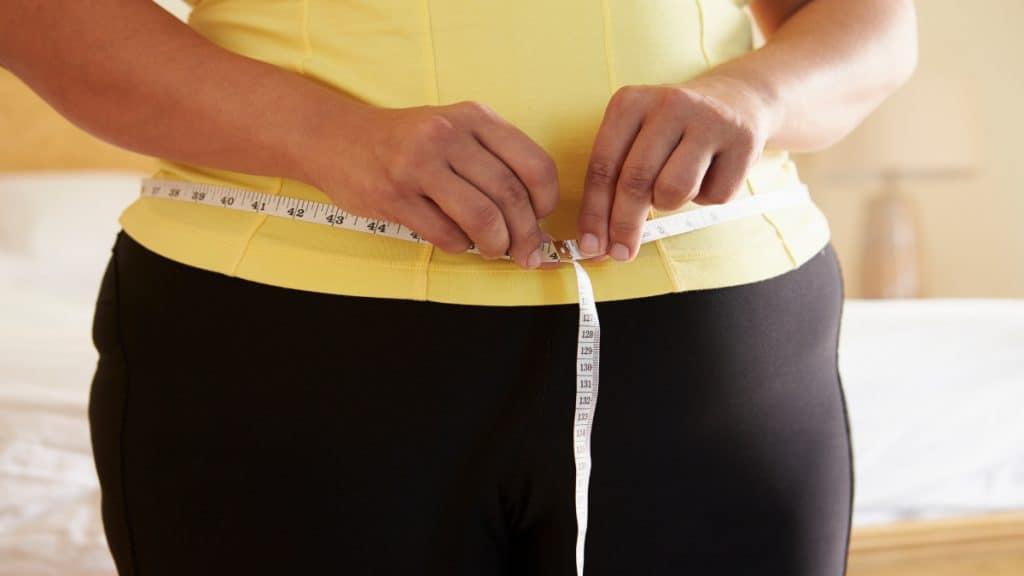 A woman measuring her 40 inch waistline