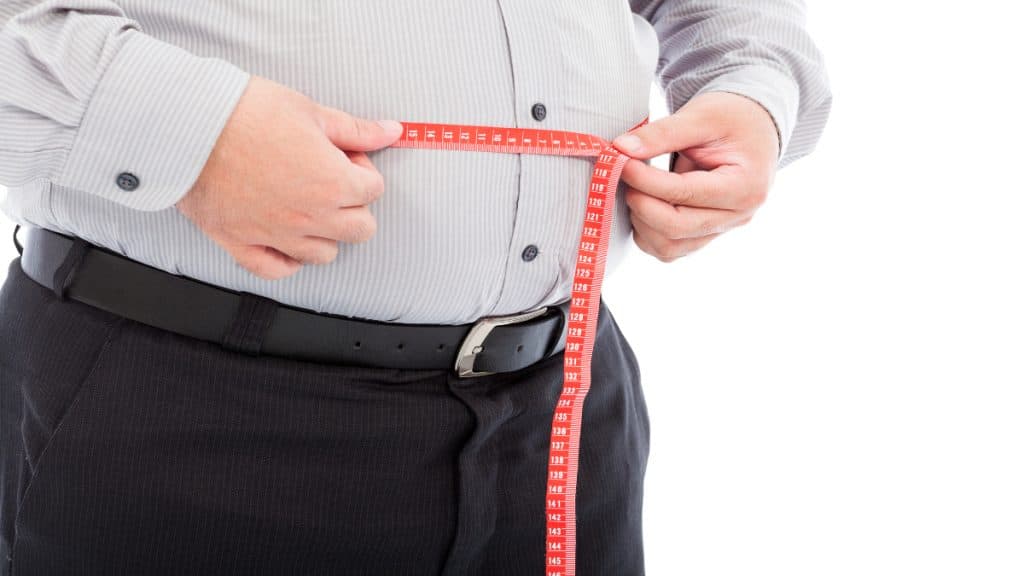 An overweight man measuring his 42 inch waist