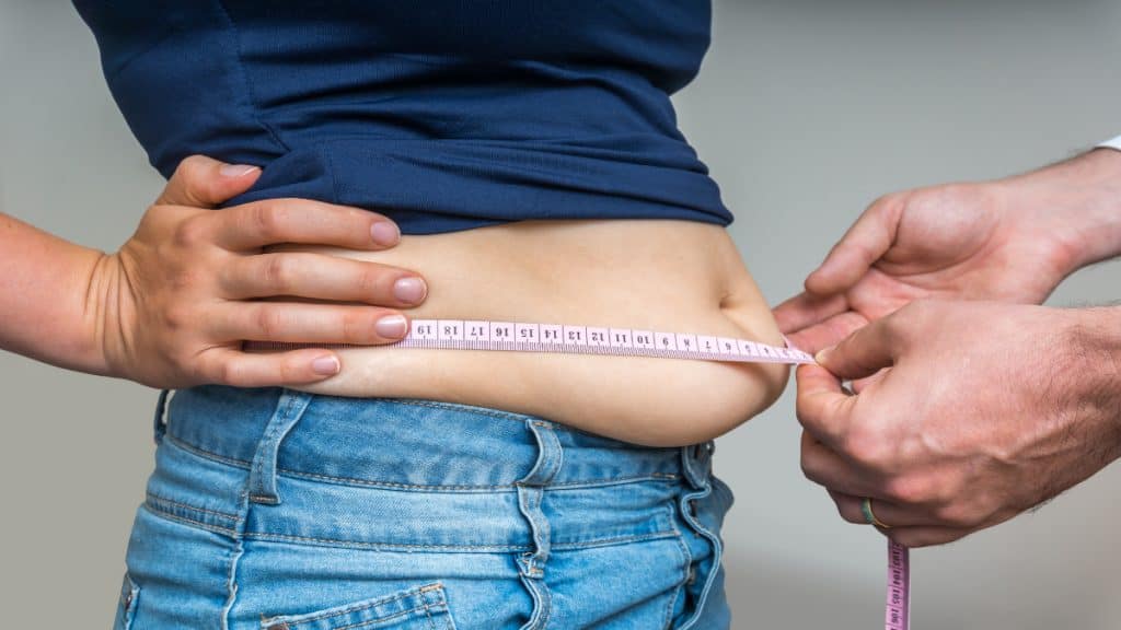 A woman with a 43 inch waist size getting measured