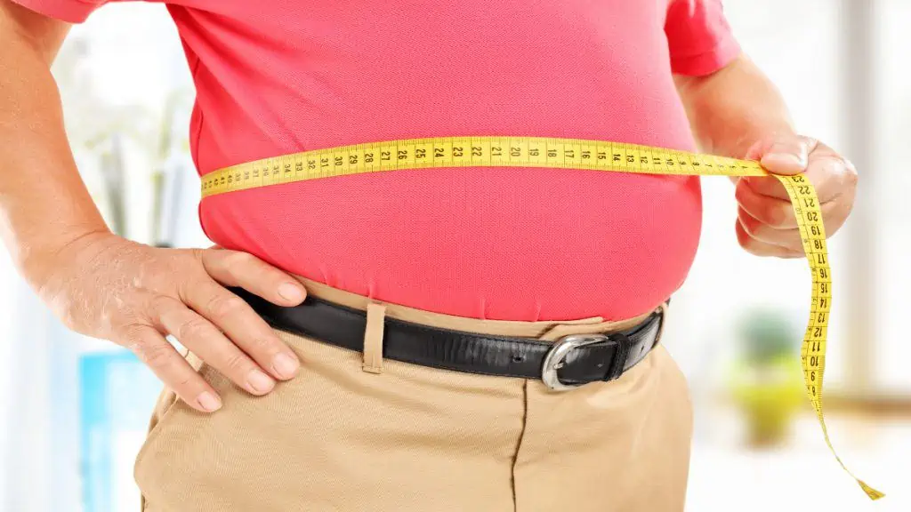 An overweight man measuring his 47 in waist