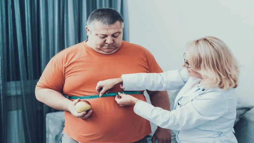 An obese man with a 47 inch waist getting his waistline measured