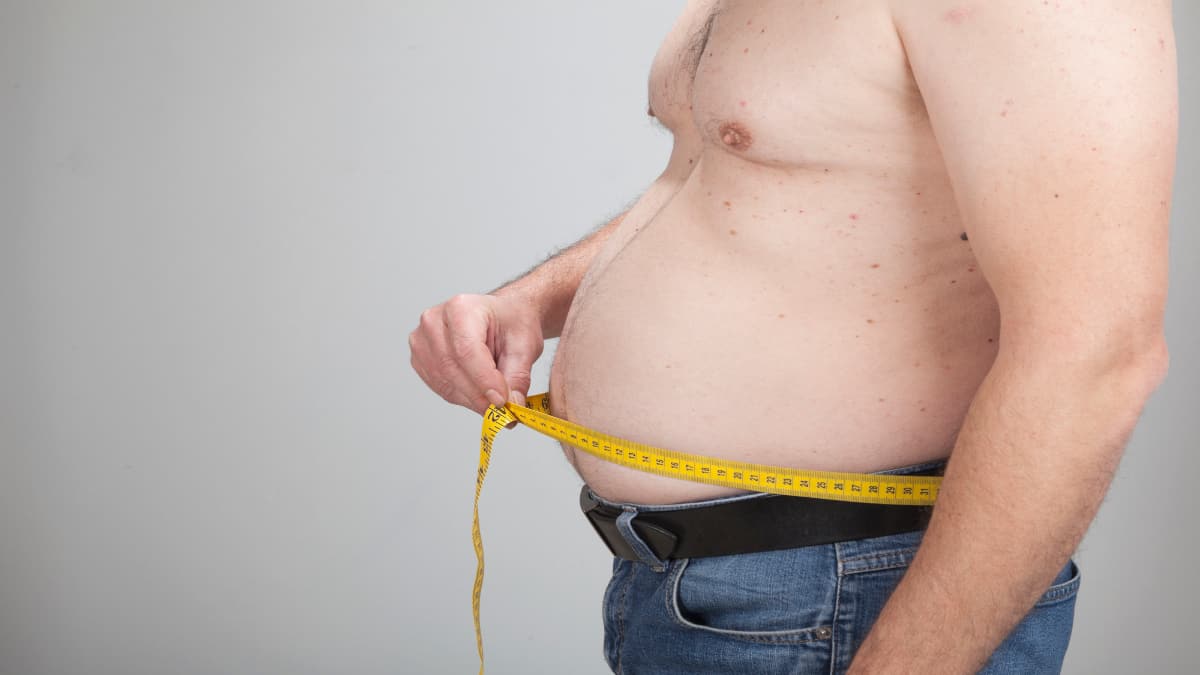 A fat man measuring his 48 inch waist