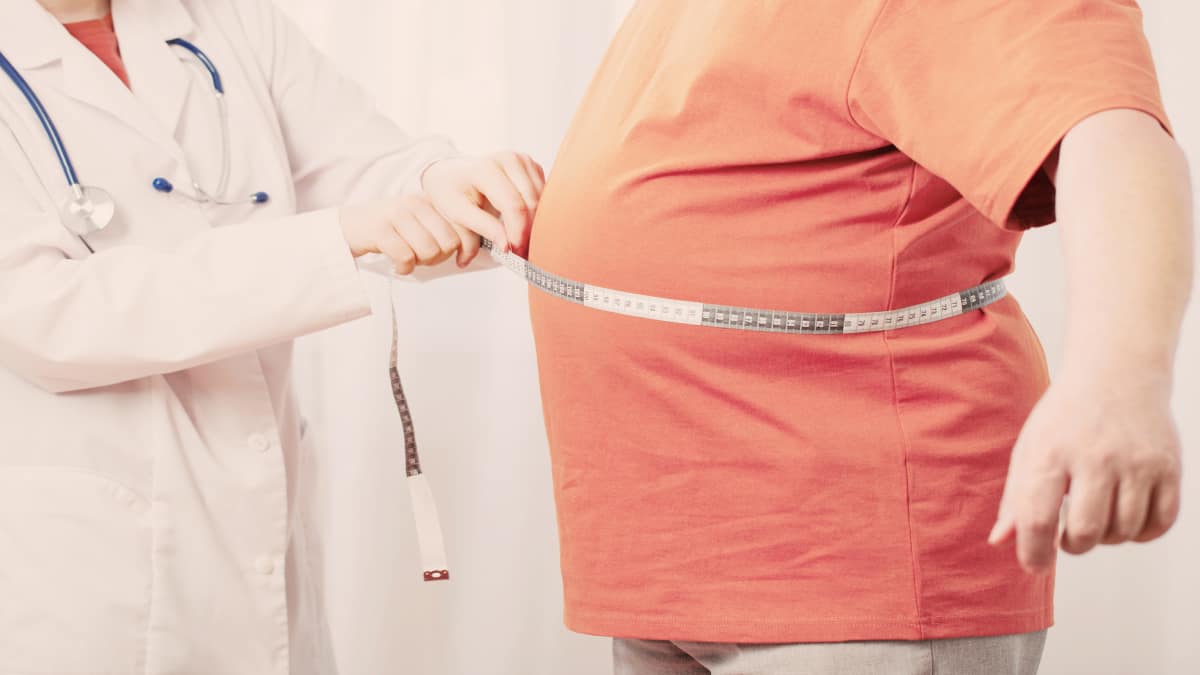 An obese man getting his 51 inch waistline measured