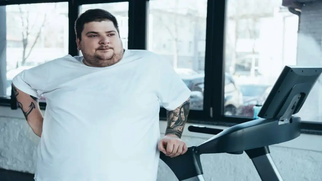 A man with a 52 in waist leaning on a treadmill