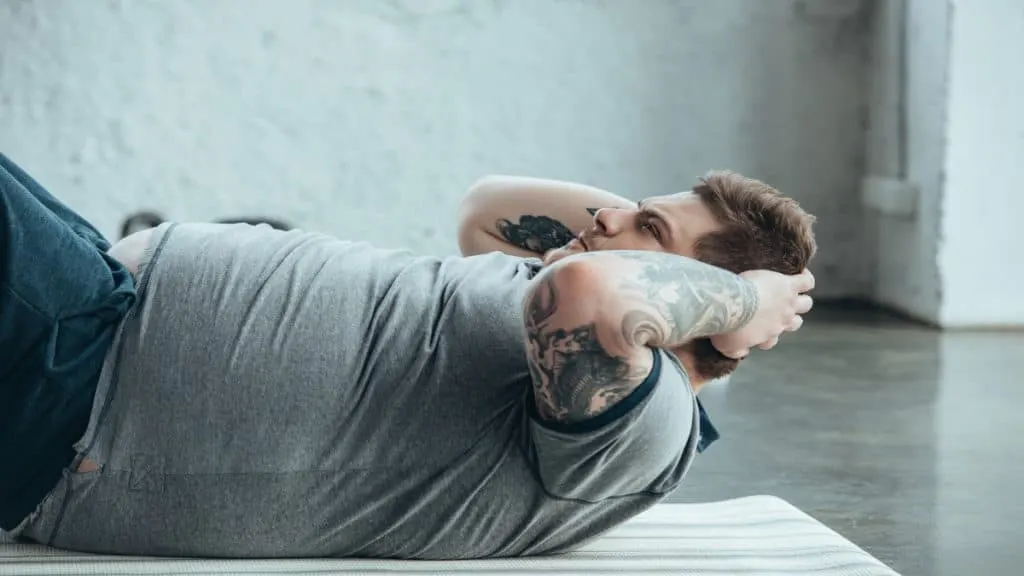 An overweight man with a 53 inch waist performing some exercise for his stomach