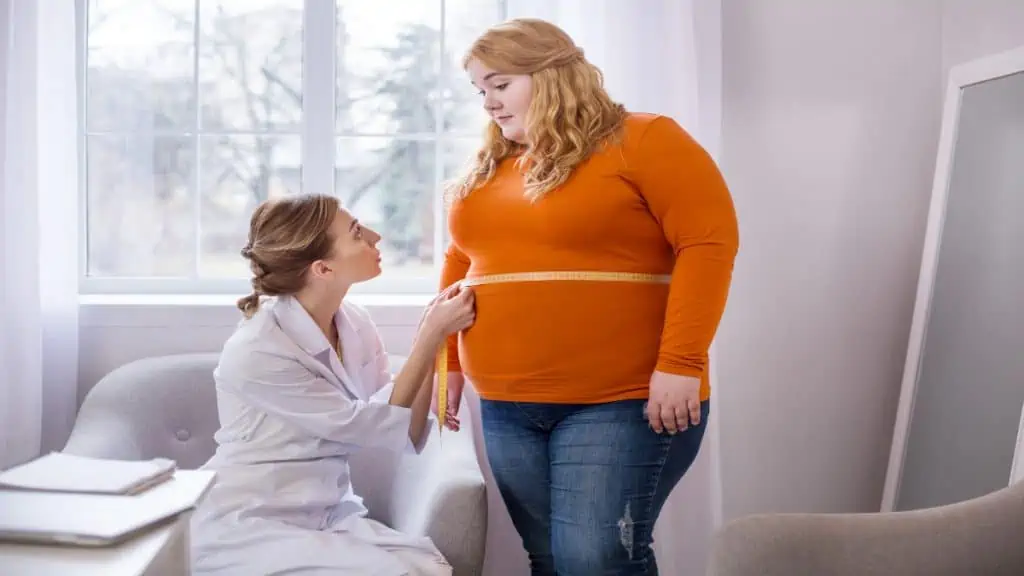 An obese woman having her 56 inch waist measured