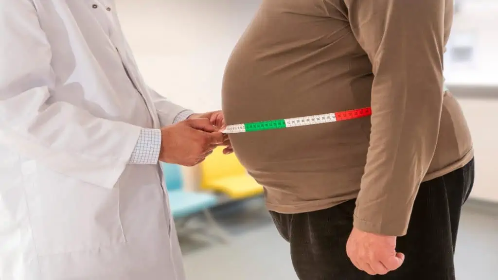 An obese man getting his 56 inch waistline measured