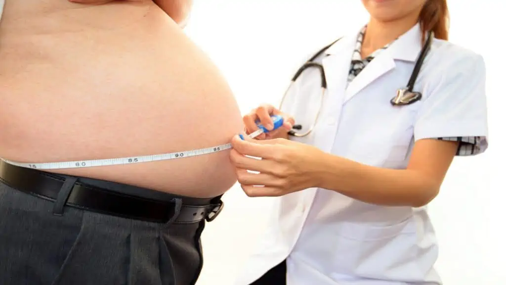 An obese man having his 59 inch belly measured