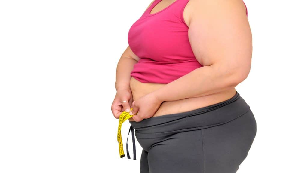 An obese woman with a 59 inch waist holding a tape measure