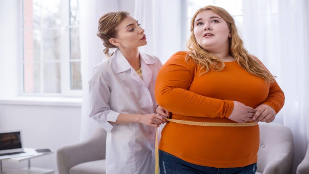 An obese woman having her 60 inch waist measured