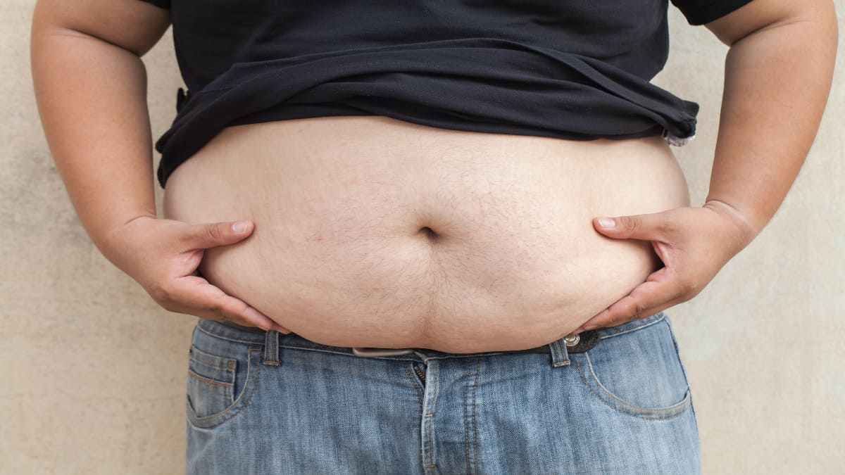 A man grabbing the fat on his big 60 inch waist