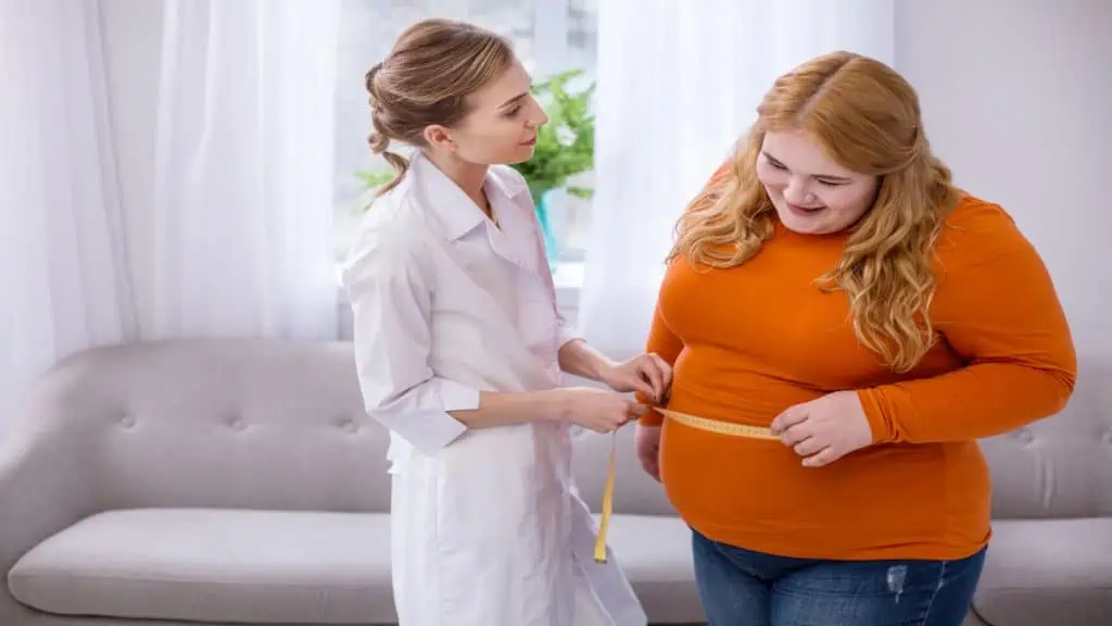 An obese woman getting her 63 inch waist measured