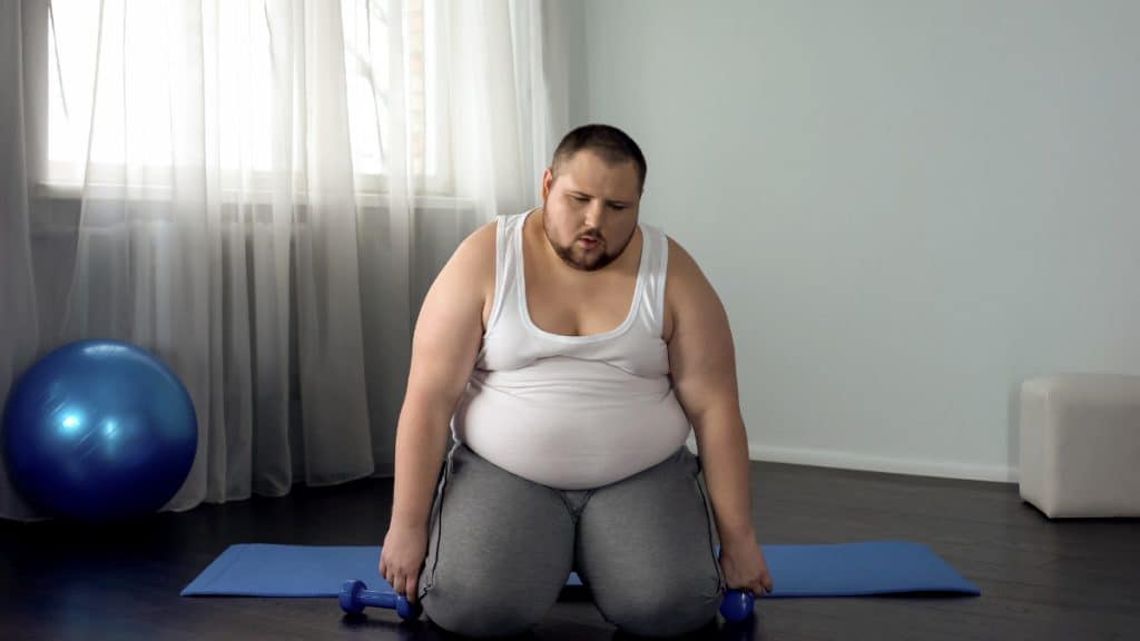 A fat man with an 80 in waist doing a workout