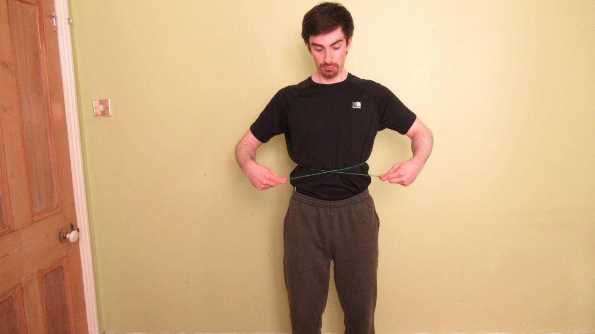 A man demonstrating how to find your waist size without a measuring tape (by using string)