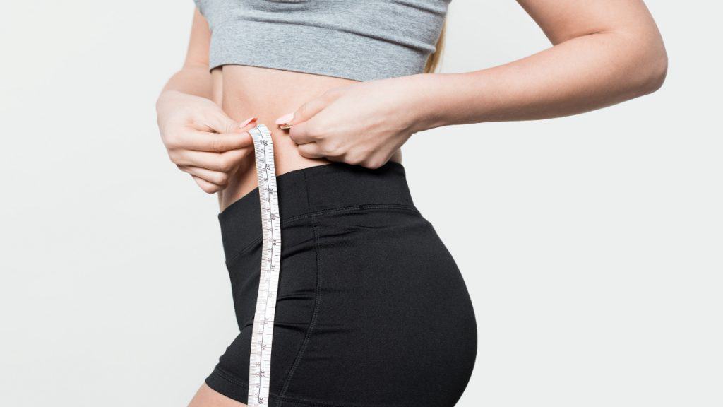 A woman measuring her 25 inch waist