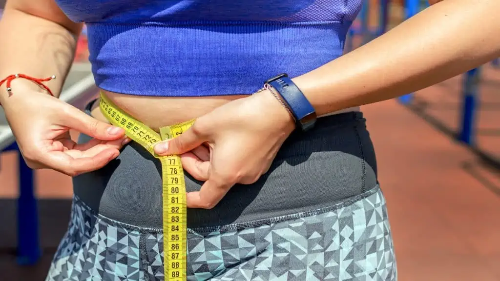 A woman measuring her big 32 inch waist